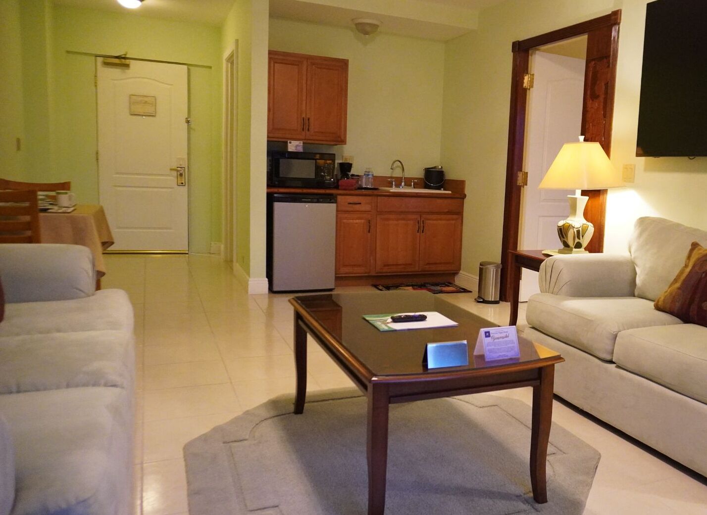 A living room with a sofa, a coffee table, and a kitchen area with wooden cabinets and appliances.