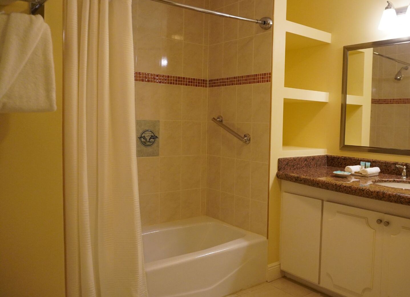 A bathroom with a bathtub, a shower, and a vanity with a mirror.