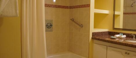A bathroom with a bathtub, a shower, and a vanity with a mirror.