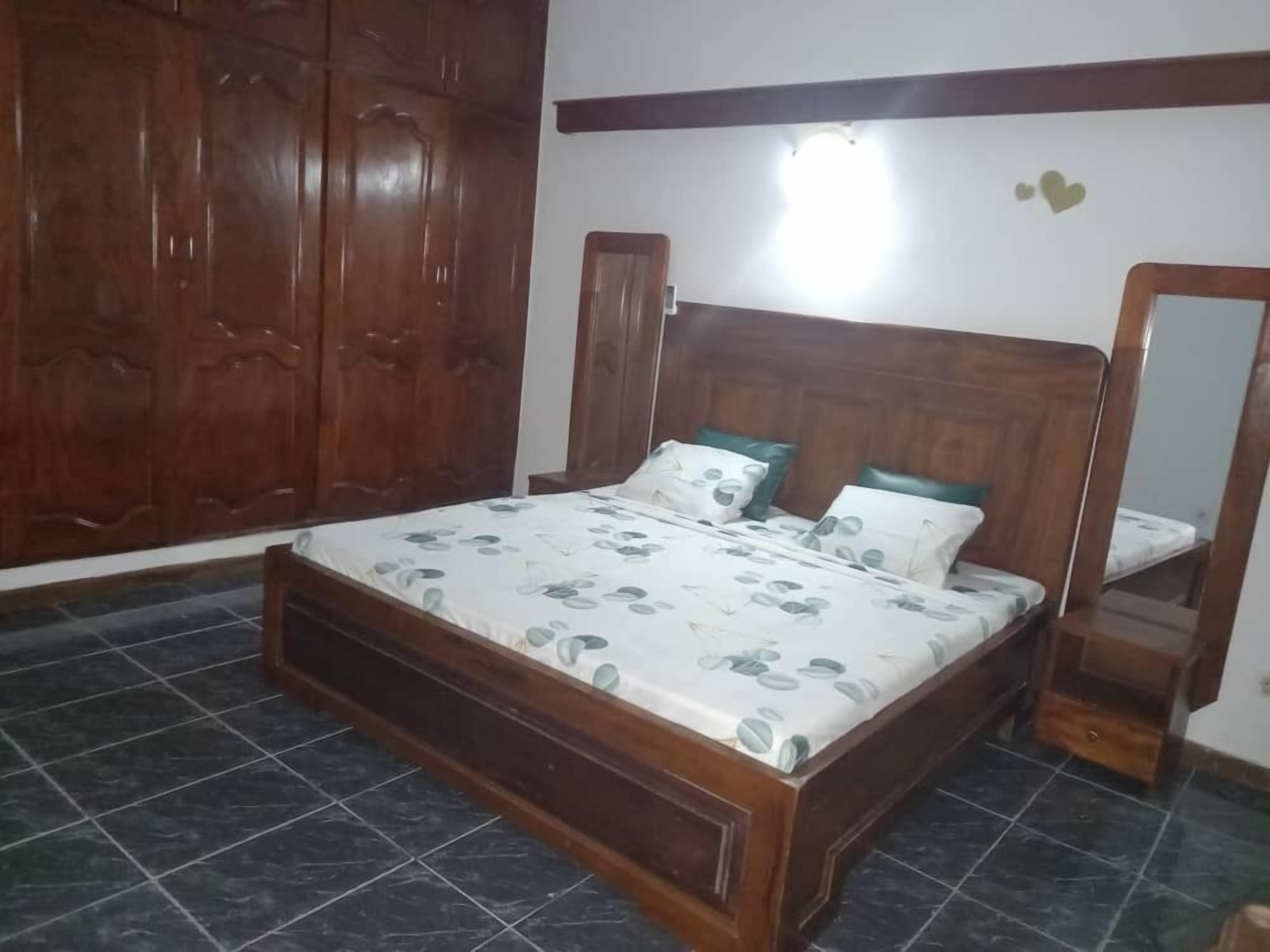 Un dormitorio con cama de madera, un armario grande y un espejo.