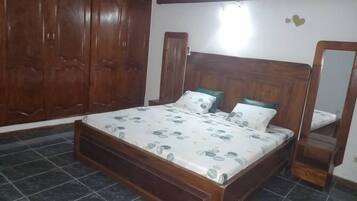 Un dormitorio con cama de madera, un armario grande y un espejo.