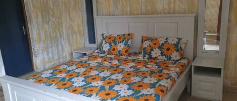 Una cama con colcha estampada, una mesita de noche y un espejo.