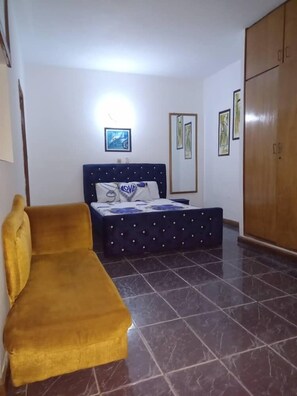 A bedroom with a bed, a wardrobe, and a sofa.
