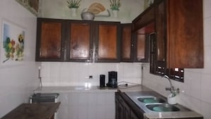 A kitchen with wooden cabinets, a coffee maker, and a sink. - Hotel Résidence Georges Colette Abidjan  (Abidjan)