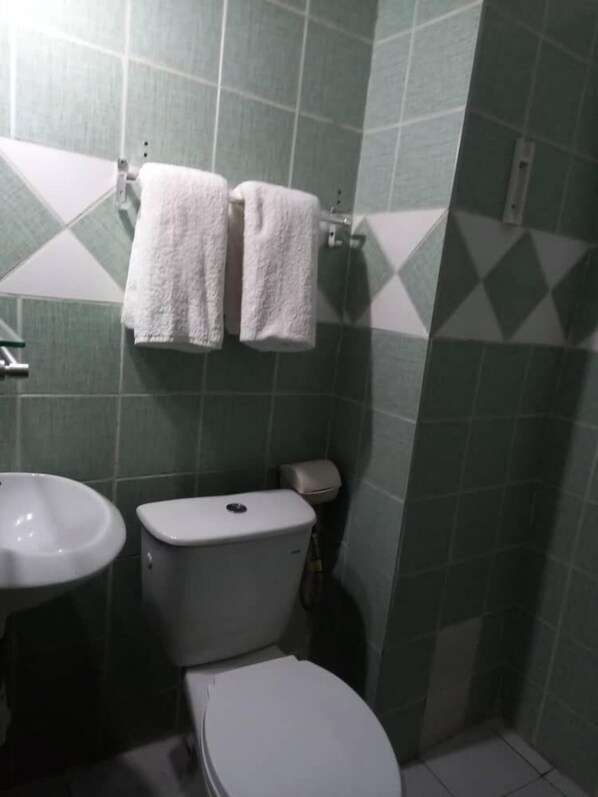 A bathroom with a toilet, sink, and two towels hanging on a rack.