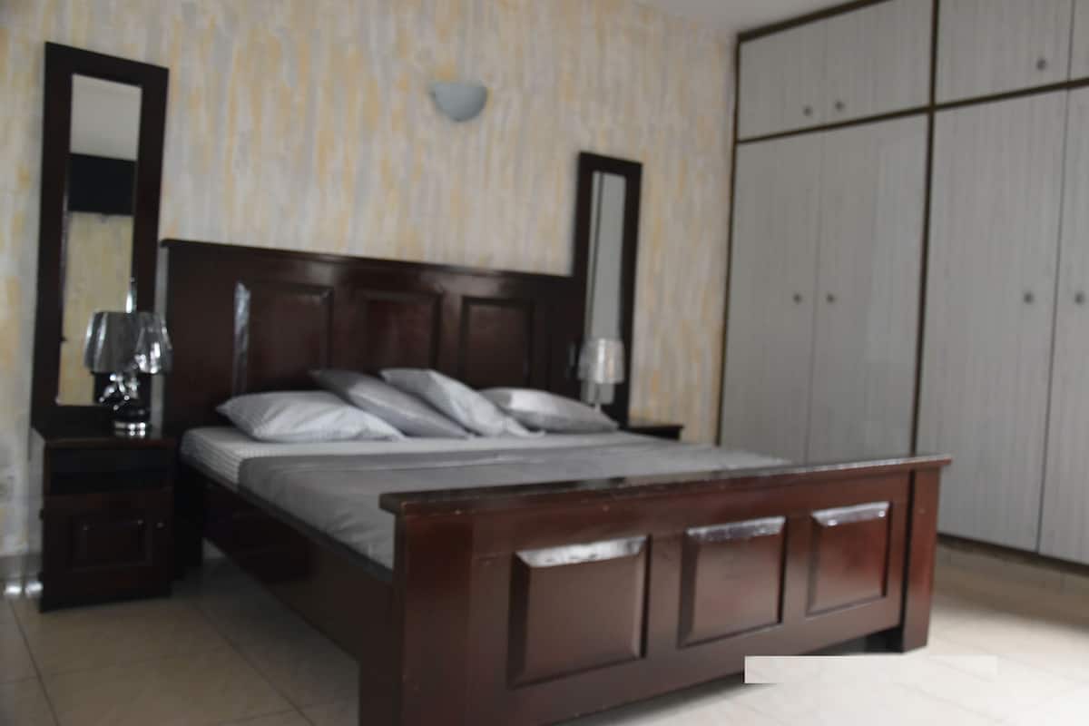 Ein Schlafzimmer mit einem hölzernen Bett, einem Nachttisch, einem Spiegel und einem Kleiderschrank.