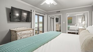A bedroom with a bed, a television, a dresser, and a balcony with curtains. - Cozy Lakefront Condo, 2BR/2BA Retreat (Hot Springs)