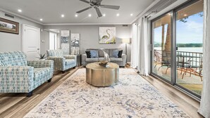 A spacious living room with a ceiling fan, a large window with a view, and a round coffee table. - Cozy Lakefront Condo, 2BR/2BA Retreat (Hot Springs)