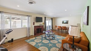 A spacious living area with a fireplace, exercise bike, and a dining area with chairs. - Modern Relaxing Retreat With Private Pool 4 Bedroom Home by RedAwning (Azusa)