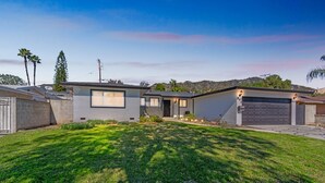 A modern two-story house with a garage, a well-maintained lawn, and a mountain backdrop. - Modern Relaxing Retreat With Private Pool 4 Bedroom Home by RedAwning (Azusa)