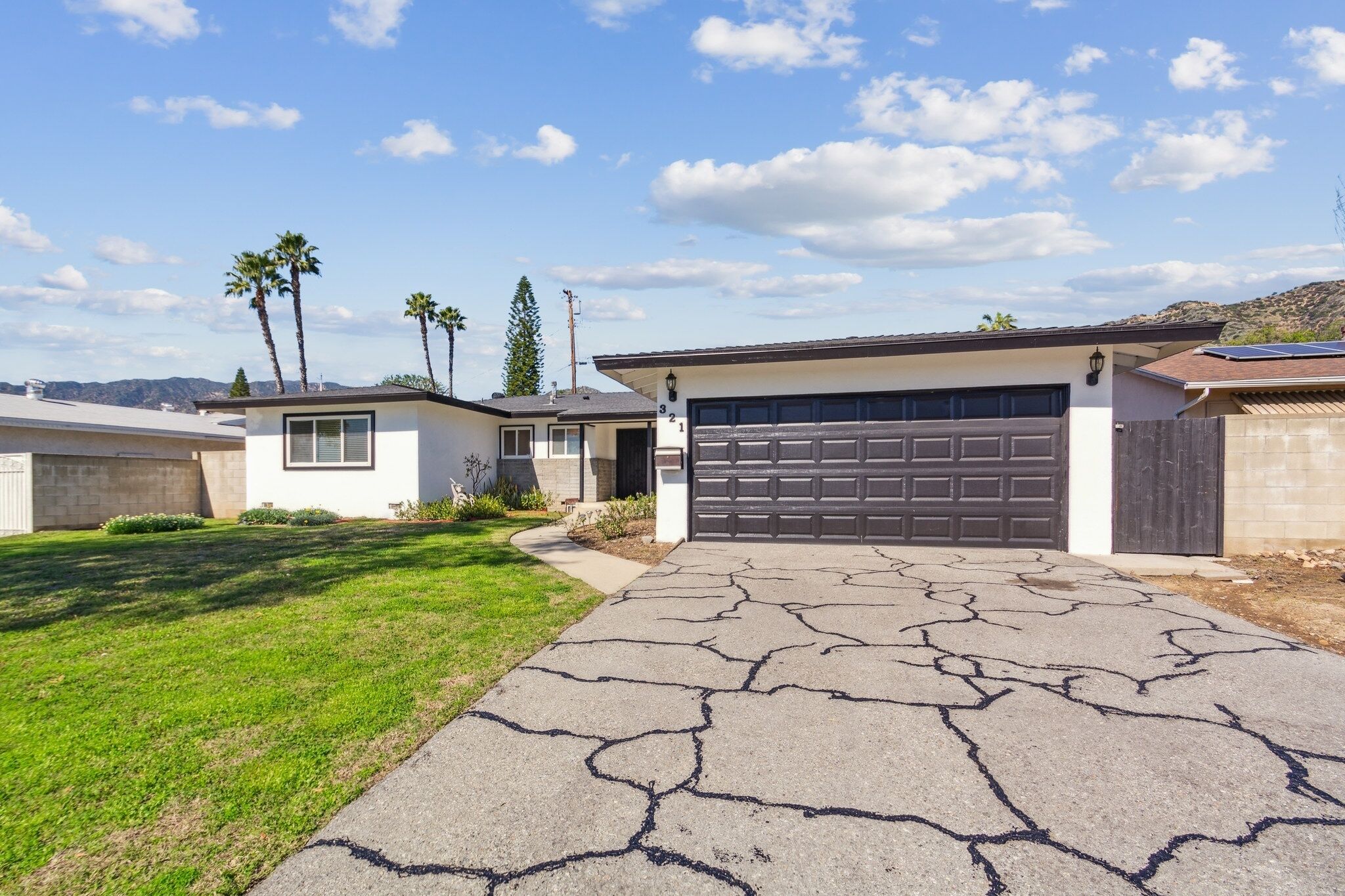 A residential driveway leading to a garage with a cracked asphalt surface.