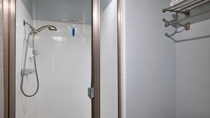 Um chuveiro envidraçado com um chuveiro manual e uma torneira fixada na parede.