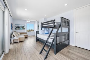 Ein modernes Schlafzimmer mit Etagenbett, einer Schlafcouch und Blick auf die Stadt.