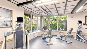 A gym with exercise equipment, large windows, and a ceiling with exposed beams.