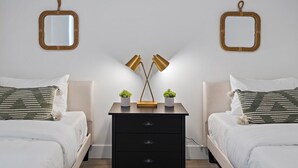 Une chambre avec deux lits, une table de chevet et deux miroirs fixés au mur.