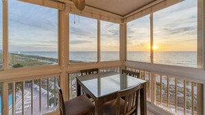 A sunroom with a glass table and chairs, large windows, and a ceiling fan. - San Marco 5th Floor With Private Beach (Venice)