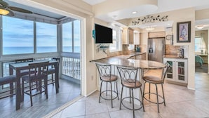 A spacious kitchen with a large island, bar stools, and a view of the ocean. - San Marco 5th Floor With Private Beach (Venice)