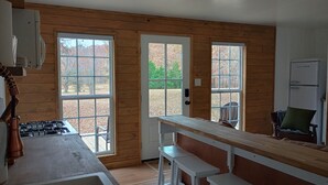 Une cabane dotée d’un coin cuisine, de murs en bois et de grandes fenêtres.