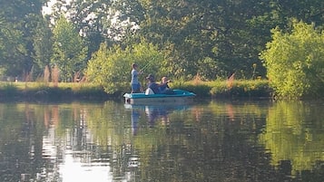 Un bateau sur une rivière paisible, bordée d’arbres des deux côtés.