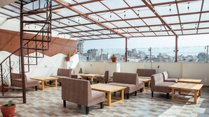 Eine Dachterrasse mit mehreren Sitzbereichen, darunter Sofas und Tische, sowie einer Treppe.