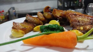 Ein Teller mit verschiedenen Speisen, darunter Fleisch, Kartoffeln und Gemüse.