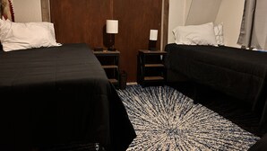 A hotel room with two beds, a wooden door, a nightstand with a lamp, and a patterned rug. - Outdoorsman's Paradise Sleeps 9 in Cedar (Cedar)