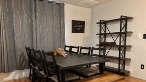 A dining area with a wooden table, chairs, and a bench. There is a decorative piece on the table and a metal shelf unit against the wall. - Outdoorsman's Paradise Sleeps 9 in Cedar (Cedar)