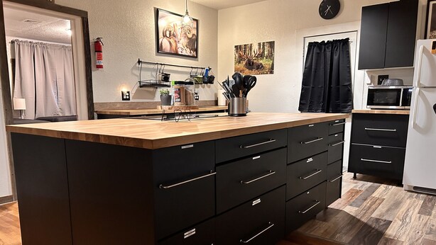 A modern kitchen with a central island, black cabinetry, and a microwave. - Outdoorsman's Paradise Sleeps 9 in Cedar (Cedar)