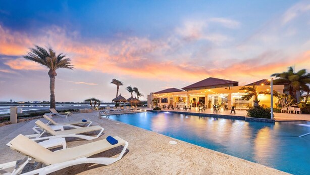 Ein Poolbereich mit Liegestühlen, einer Bar und Blick auf den Sonnenuntergang.