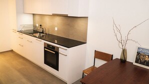 Uma cozinha moderna com armários brancos, bancada preta e forno embutido.
