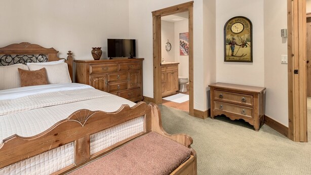 A bedroom with a wooden bed, a TV, a dresser, and a small cabinet. - Steamboat in Style! Dog Friendly, Walk to Resort, Hot Tub, Great Views, Locker (Steamboat Springs)