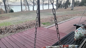 Una terraza de madera con un columpio que da a un cuerpo de agua.