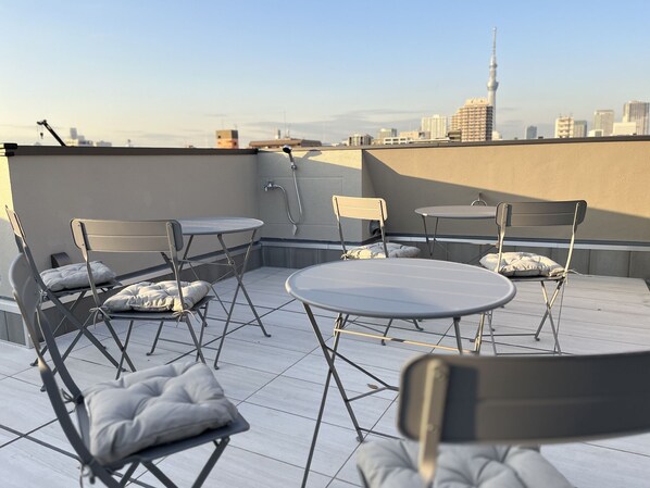 Una terraza en la azotea con sillas plegables y una mesa, una fuente de agua y el horizonte de la ciudad al fondo.