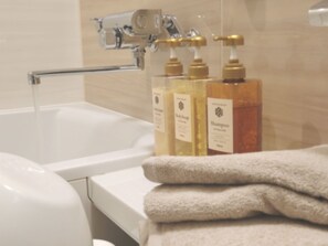 Un baño con una bañera, un grifo y dos botellas de champú.