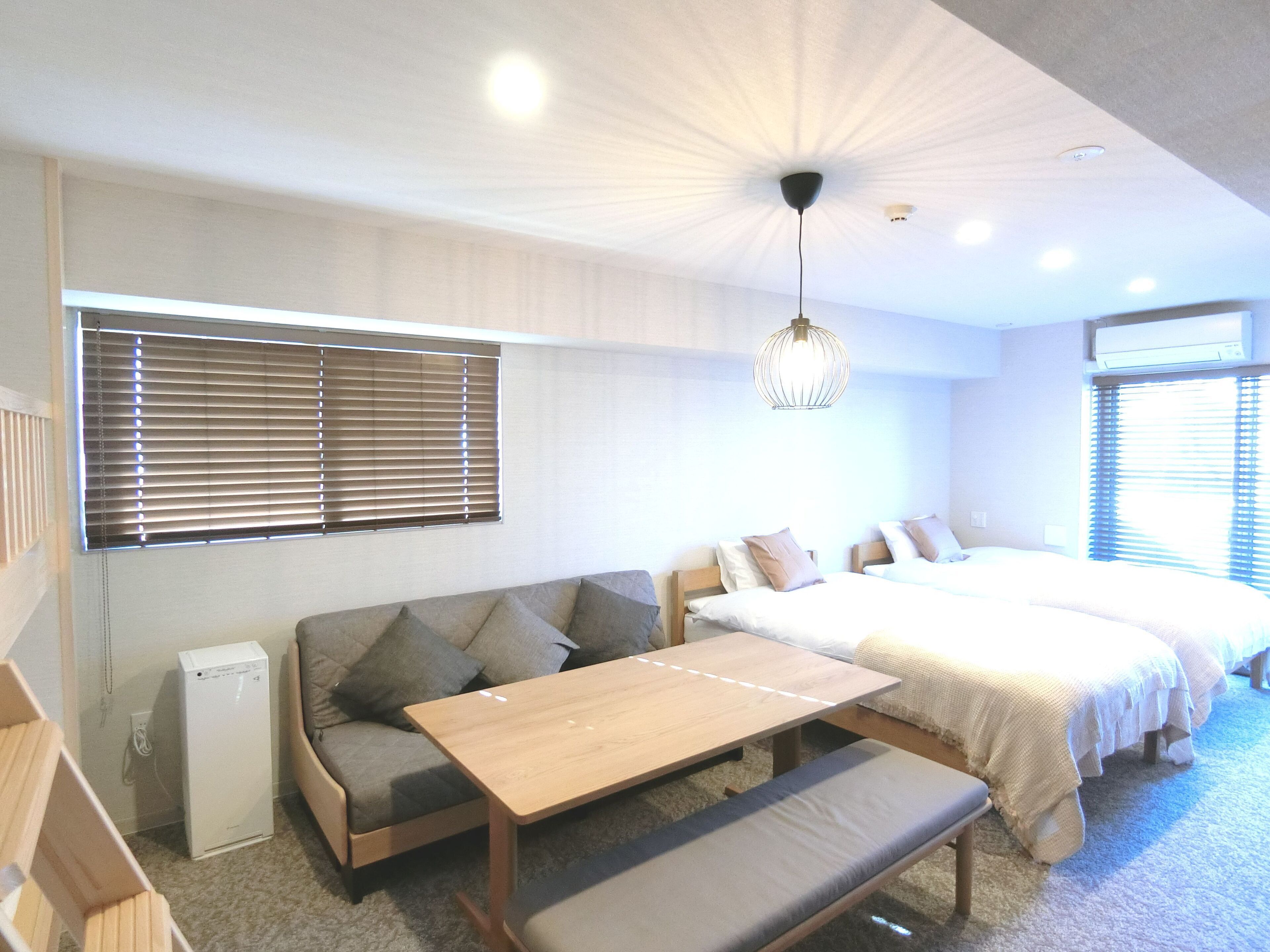 Een moderne slaapkamer met een bank, een houten tafel en een bed met twee kussens.
