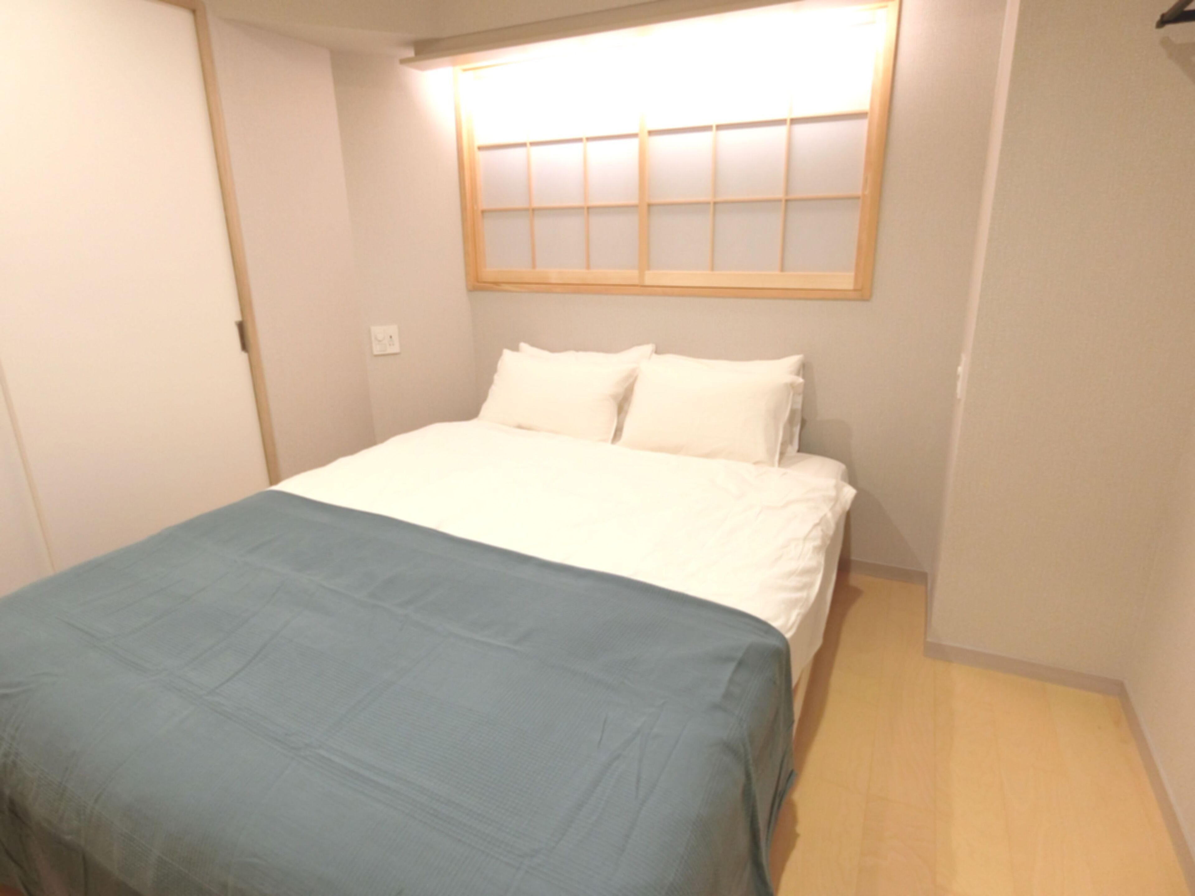 A bedroom with a bed, a window, and a door.