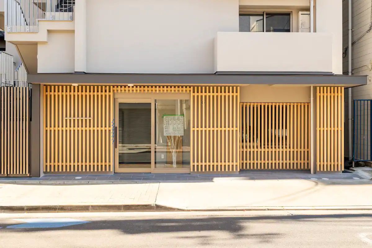 Un bâtiment moderne à la façade plate, doté de grandes fenêtres en verre et d’une entrée avec des lambris en bois.
