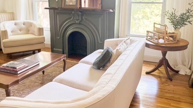Un salon avec une cheminée, un canapé, un fauteuil et une petite table.
