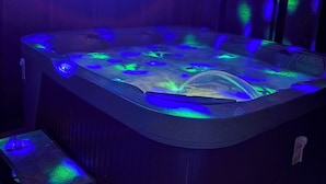 Un jacuzzi con iluminación azul y verde, una mesita con un mapa y un armario de madera.