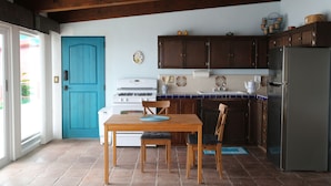 A kitchen with wooden cabinets, a blue door, a refrigerator, and a stove.