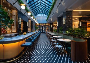 Eine moderne Bar mit hoher Decke, geometrischem Bodenmuster und verschiedenen Sitzmöglichkeiten.