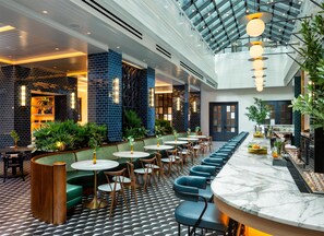 A modern interior with a long bar, seating areas, and a high ceiling with skylights. - 1-Bedroom Suite at a 4⭐️ Hotel (Nashville)