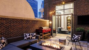 An outdoor seating area with a fire pit, a barbecue grill, and a sofa with patterned cushions. - 1-Bedroom Suite at a 4⭐️ Hotel (Nashville)