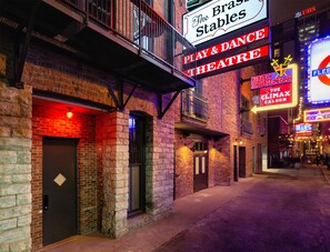 Un edificio de ladrillo con un cartel que dice 'The Brass Stables', indicando un teatro de obras y danza.