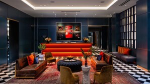 Un vestíbulo moderno con piso a cuadros, sofás, un mostrador de recepción rojo y un gran ventanal.