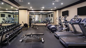 Un gimnasio bien equipado con cintas de correr, máquinas de pesas y pesas libres.