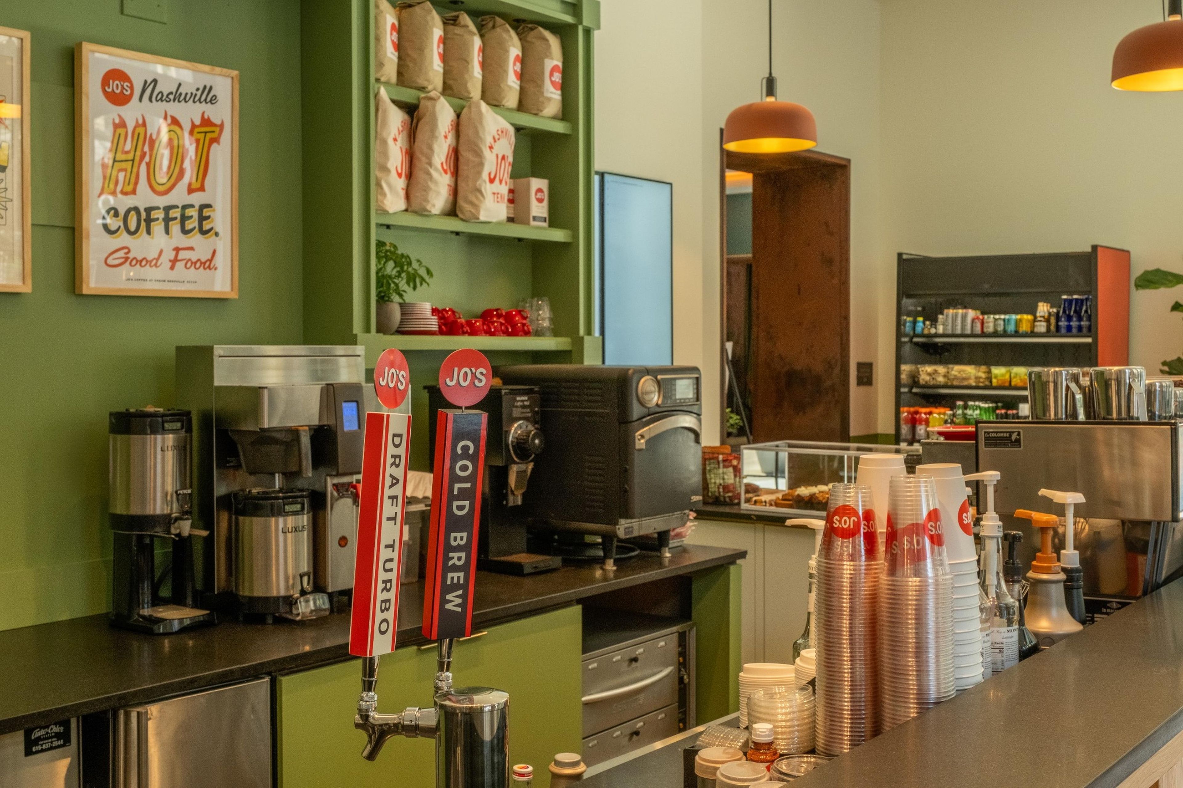 L’intérieur d’un café, avec un comptoir, des machines à café et une variété de tasses et de bouteilles à café.
