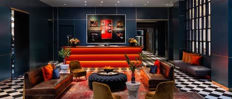 A modern lobby with a checkered floor, sofas, a red reception desk, and a large window.