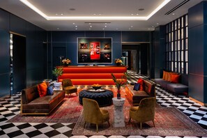 Eine moderne Lobby mit Schachbrettfußboden, Sofas, einem roten Empfangstresen und einem großen Fenster.