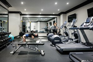 Una palestra con diverse attrezzature per esercizi, tra cui tapis roulant, vogatore e pesi liberi.